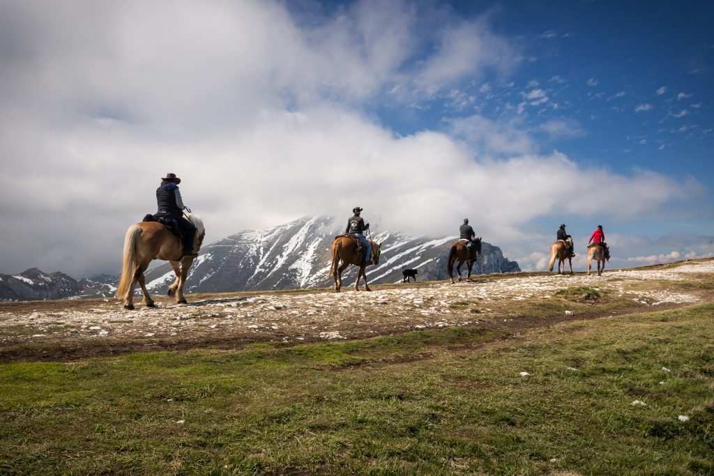 Gruppe von Reitern mit ihren Pferden, in den Bergen